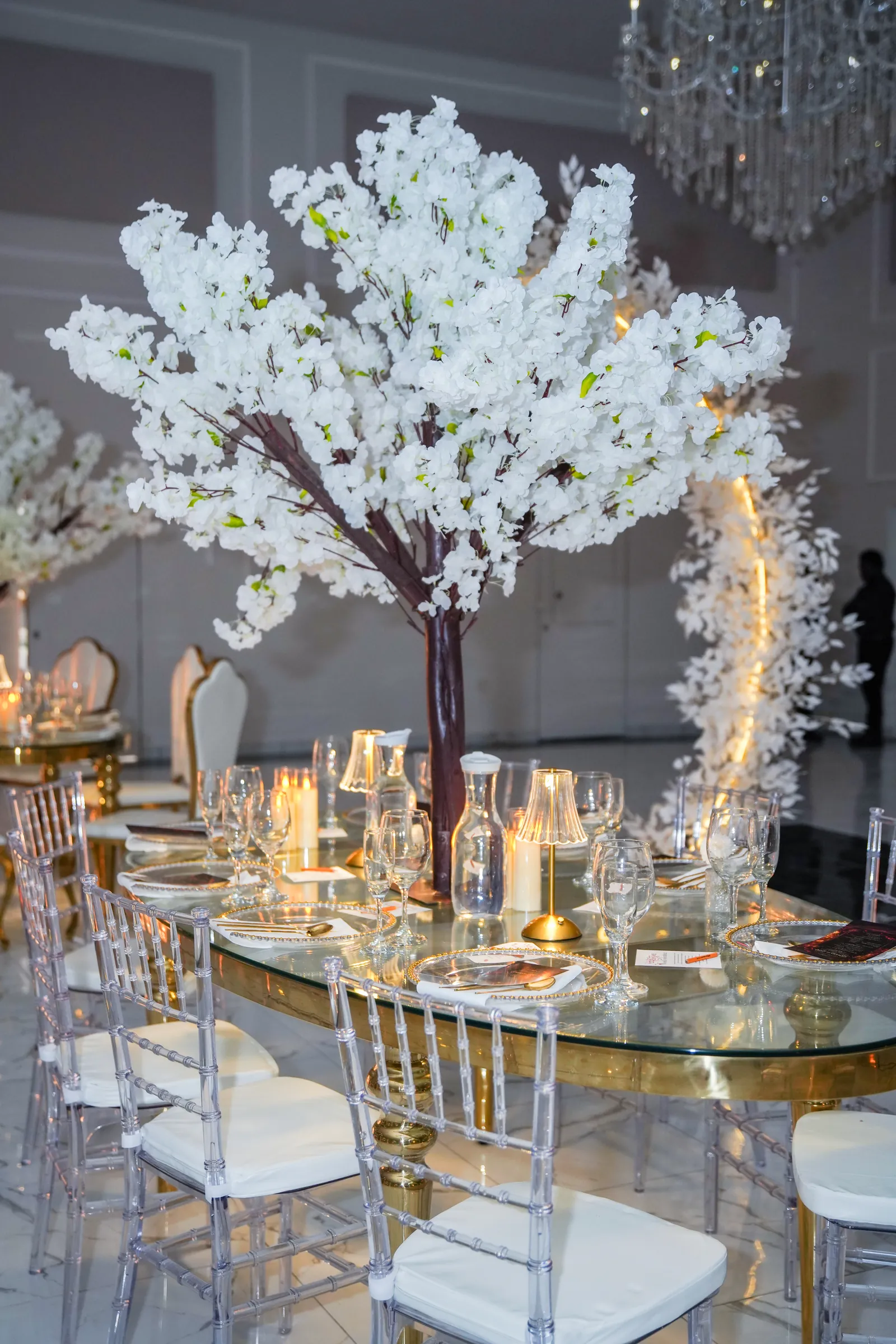 Long table set in gold and white beneath a floral arch