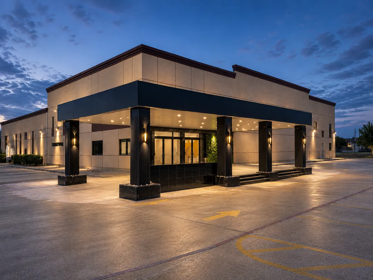 Heritage Hall at dusk: cream stone panels, black banding and a lit porte-cochere